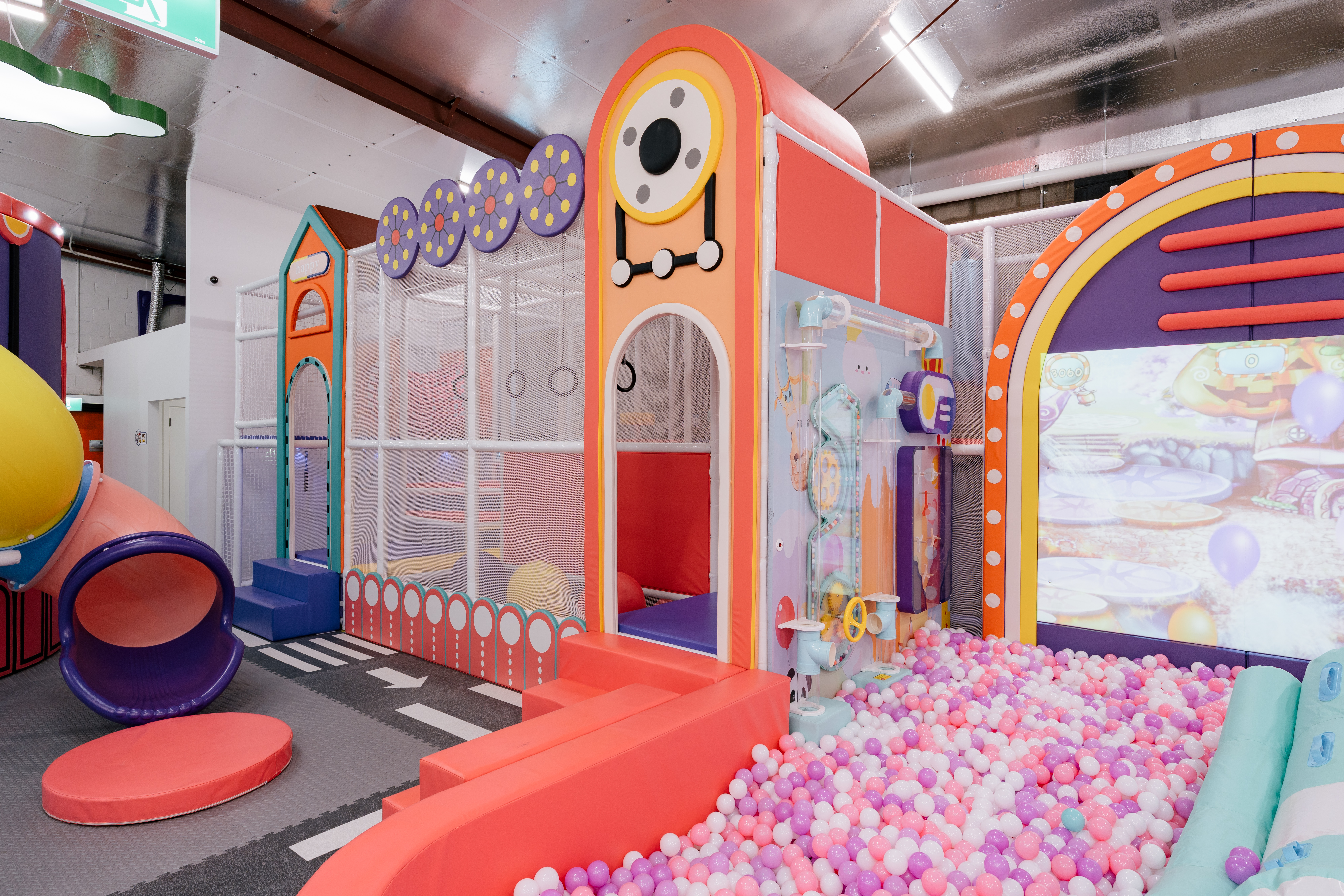 Children climbing and moving through a warm-toned adventure play area inside the venue.