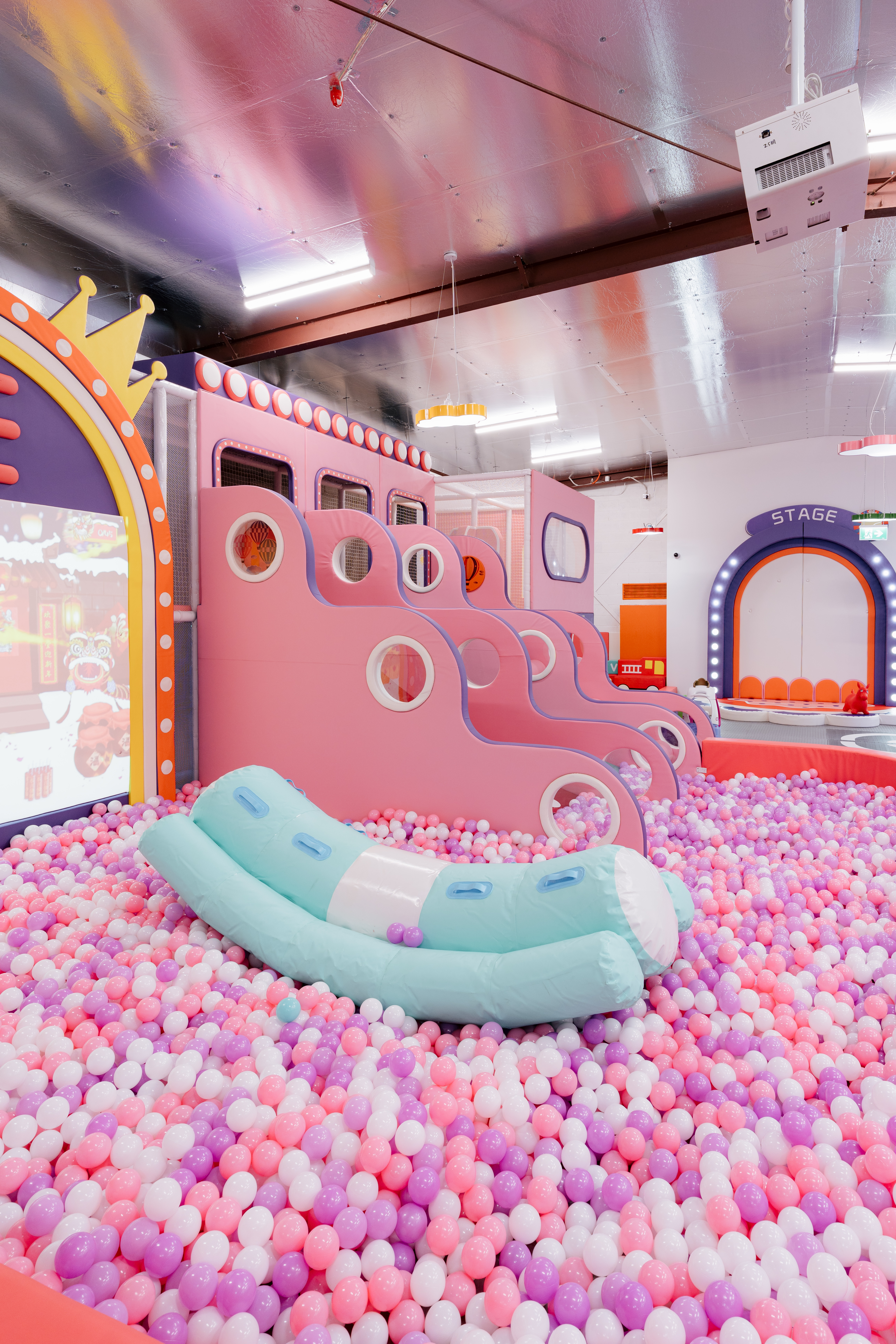 A soft baby play corner with cushioned shapes, pastel toys, and a calm cosy atmosphere.